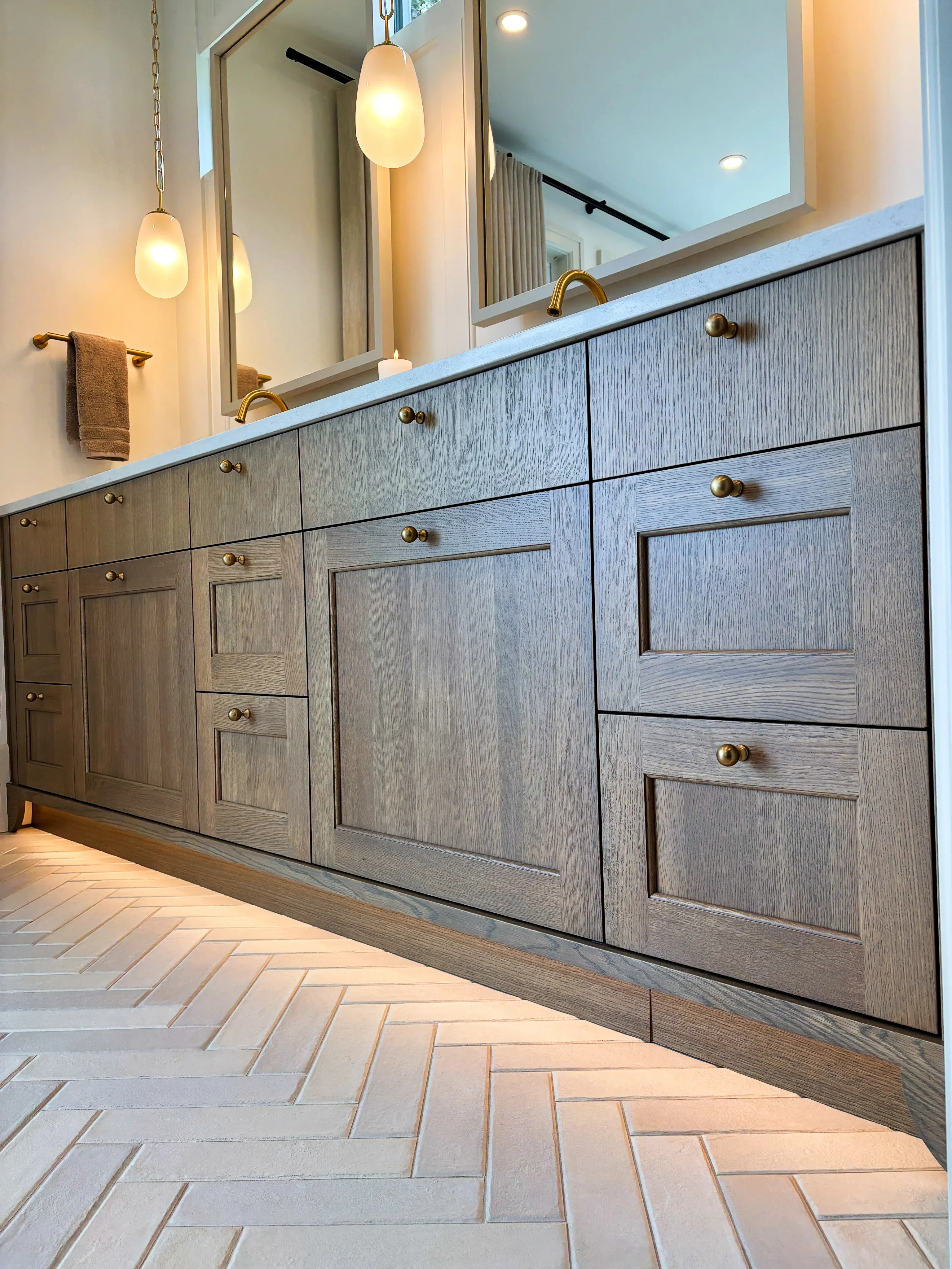 Swick Road ensuite vanity as built — custom oak cabinetry with brass hardware and herringbone tile floor