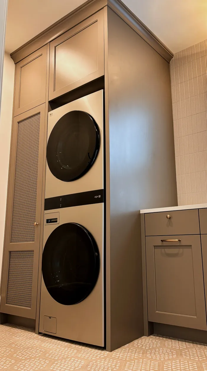 Swick Road laundry room — built-in tower with integrated appliances, floor-to-ceiling cabinetry, and decorative tile floor