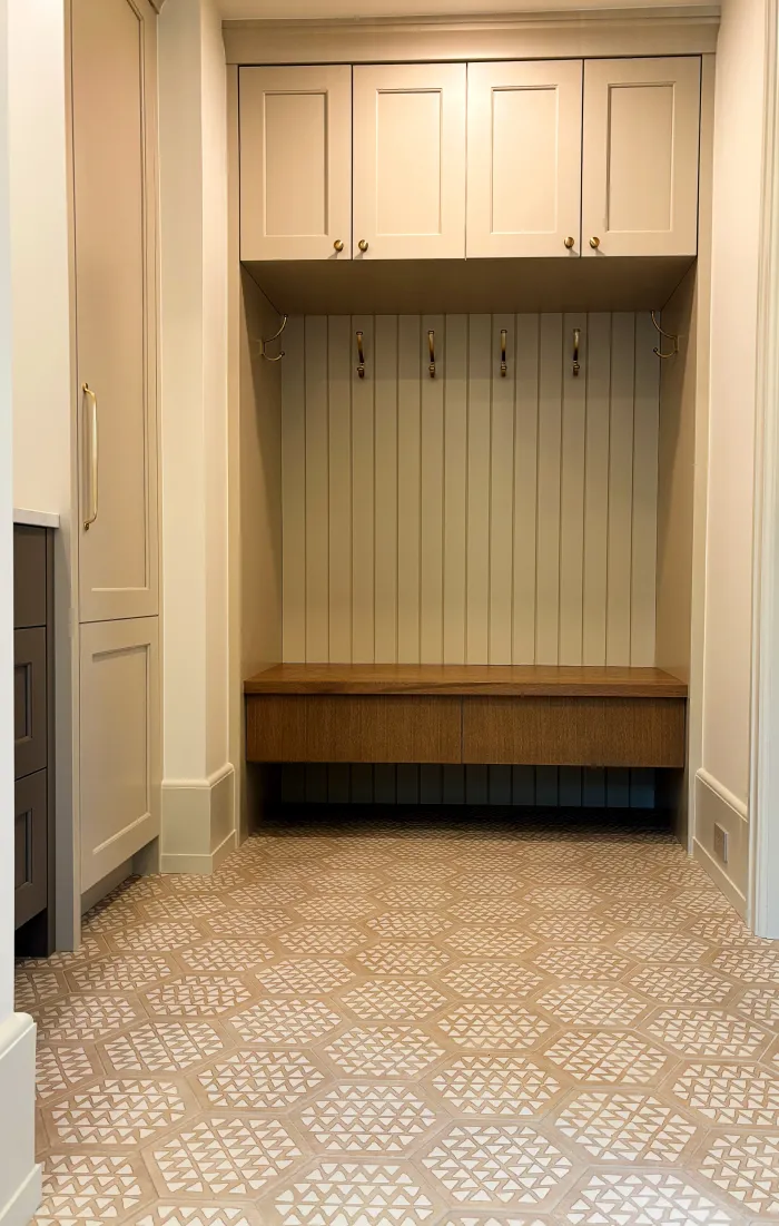 Swick Road mudroom — built-in locker with upper painted cabinets, brass coat hooks, and oak bench