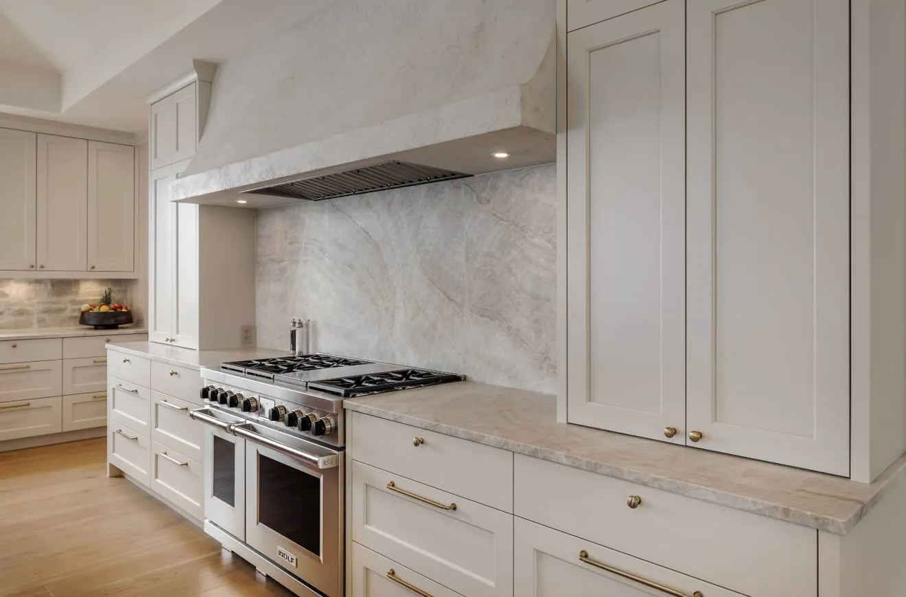 Swick Road range wall as built — custom painted cabinetry flanking a Wolf range with custom stone surround